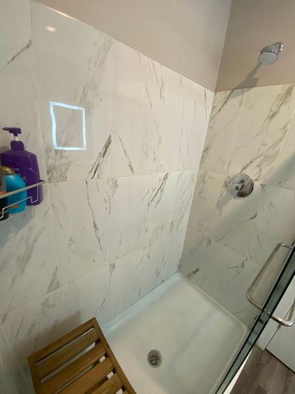 A bathroom with a walk in shower and a wooden bench.