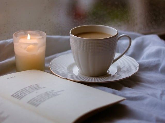 A cup beside a candle and a book creates comforting scene for cremation services Emmitsburg, MD