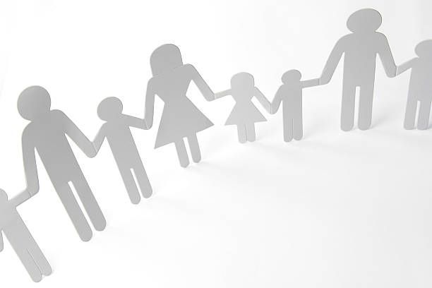 Paper cut-out figures of a family holding hands, arranged in a row.