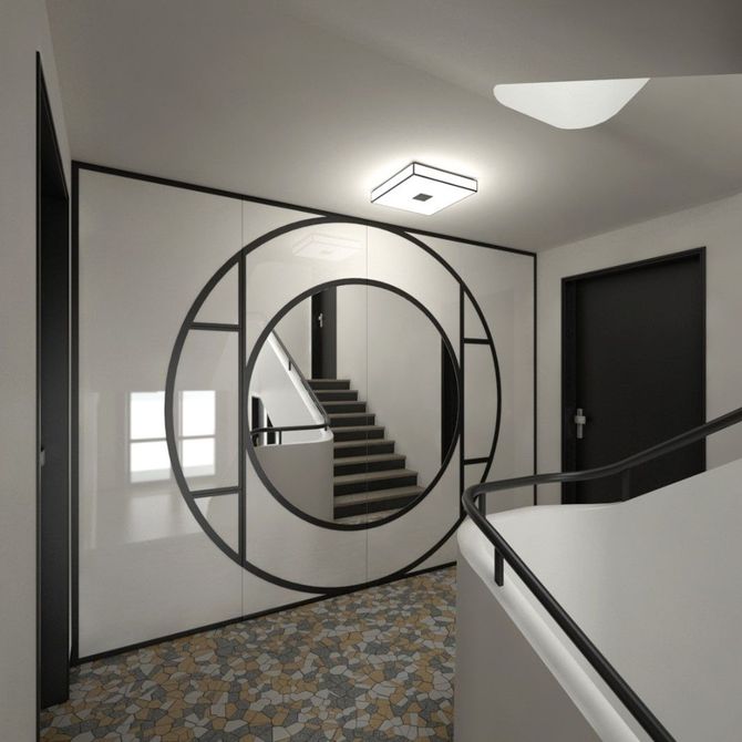 Couloir moderne avec moquette à motifs, portes noires et miroir mural circulaire reflétant un escalier.
