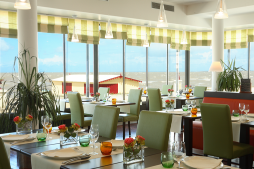 Un restaurant avec des tables et des chaises et une vue sur l'océan  réalisé par mes services d'architecte d'intérieur