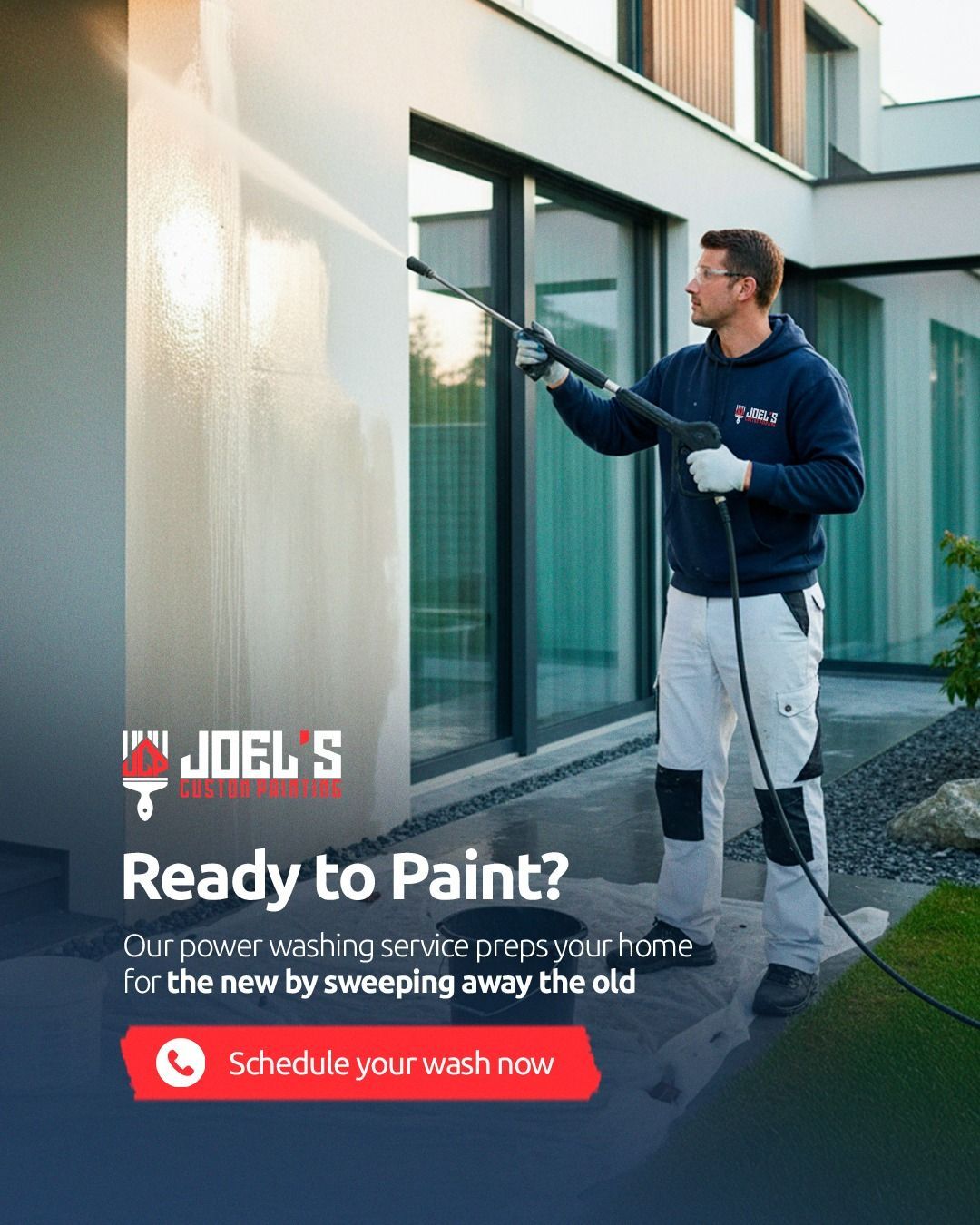A worker in a blue hoodie and white pants uses a power washer to clean the exterior wall of a modern home.