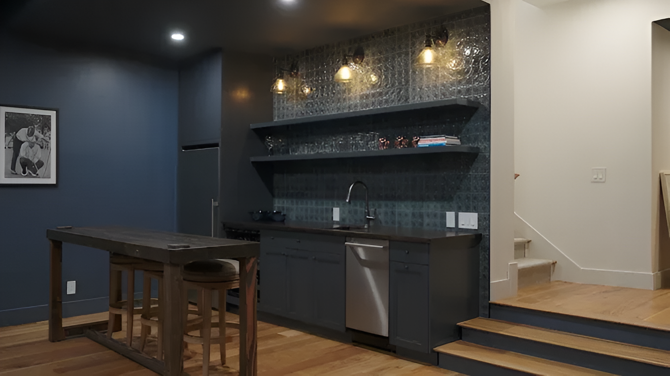 A modern basement wet bar with dark blue cabinets, open shelving, a stainless dishwasher, and a wooden island.
