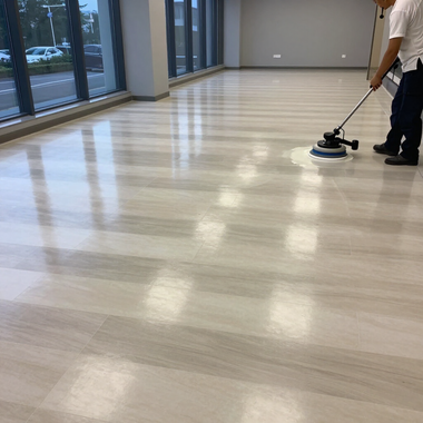 Person buffing a shiny wood floor in a bright empty room