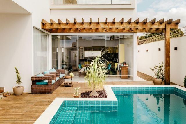 There is a large swimming pool in the backyard of a house.