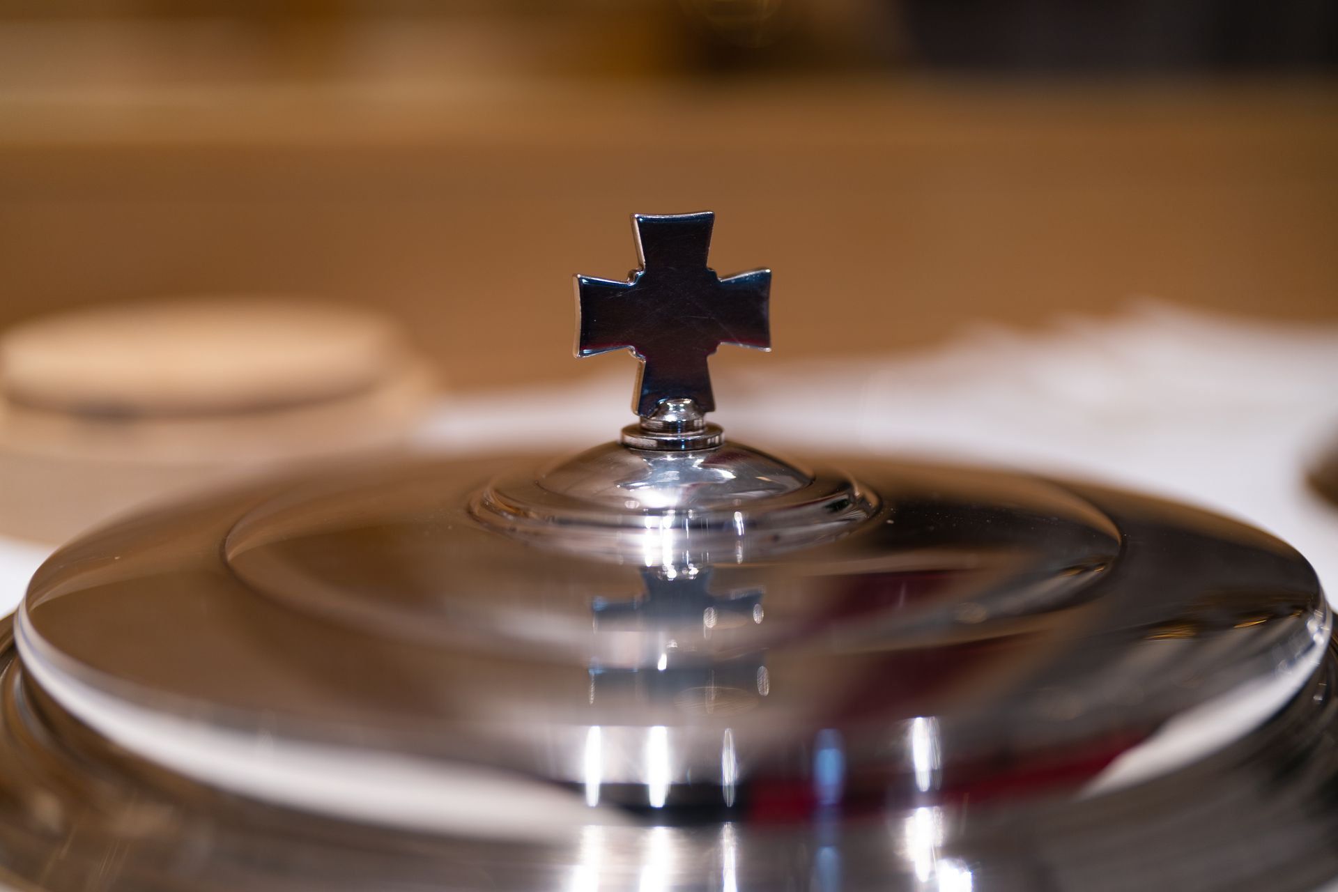 Silver communion chalice with cross on top.
