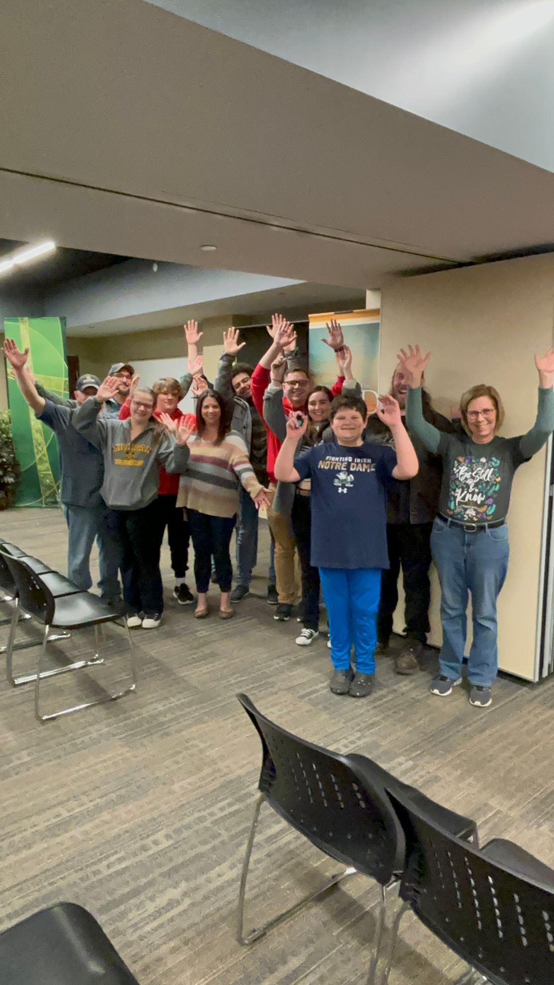 Group of people standing with arms raised in an indoor setting.