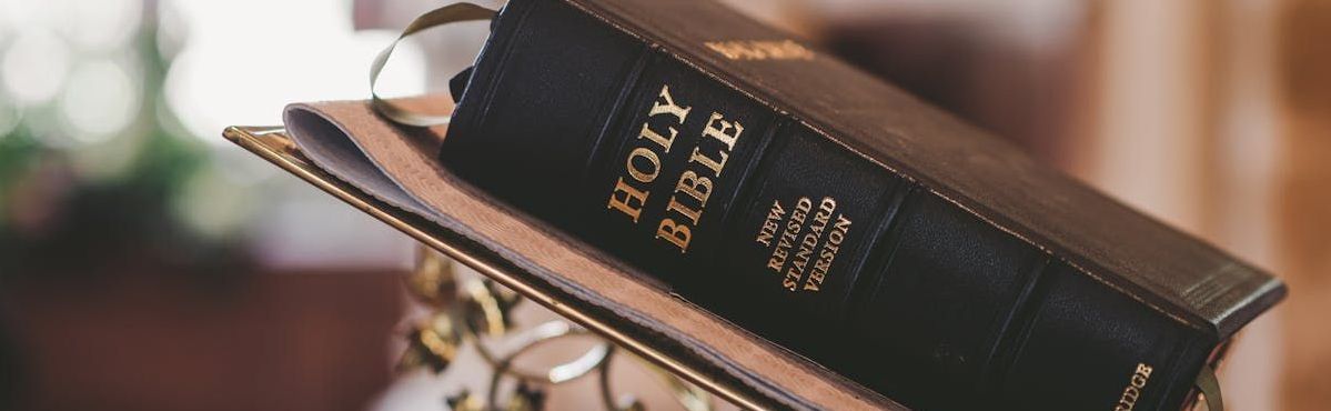 Black Bible with gold lettering on a book holder, likely at a church.