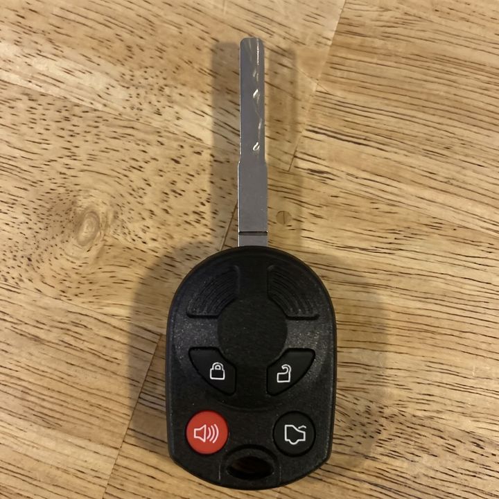 Black car key fob with silver key blade on a wooden surface