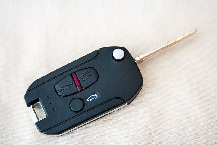 Black car key with flip-out metal blade on a light background