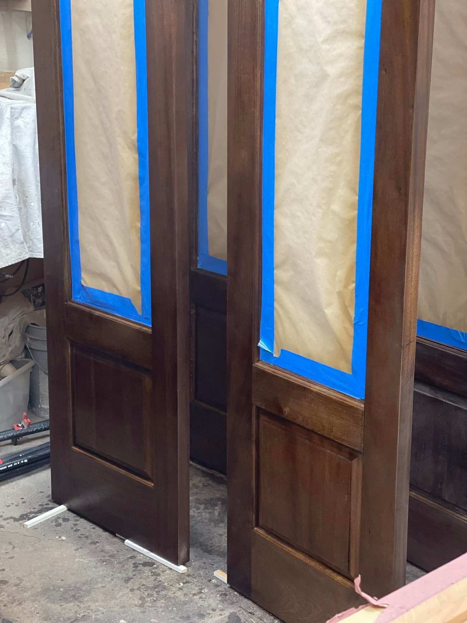 Two stained wooden doors with taped glass panels.