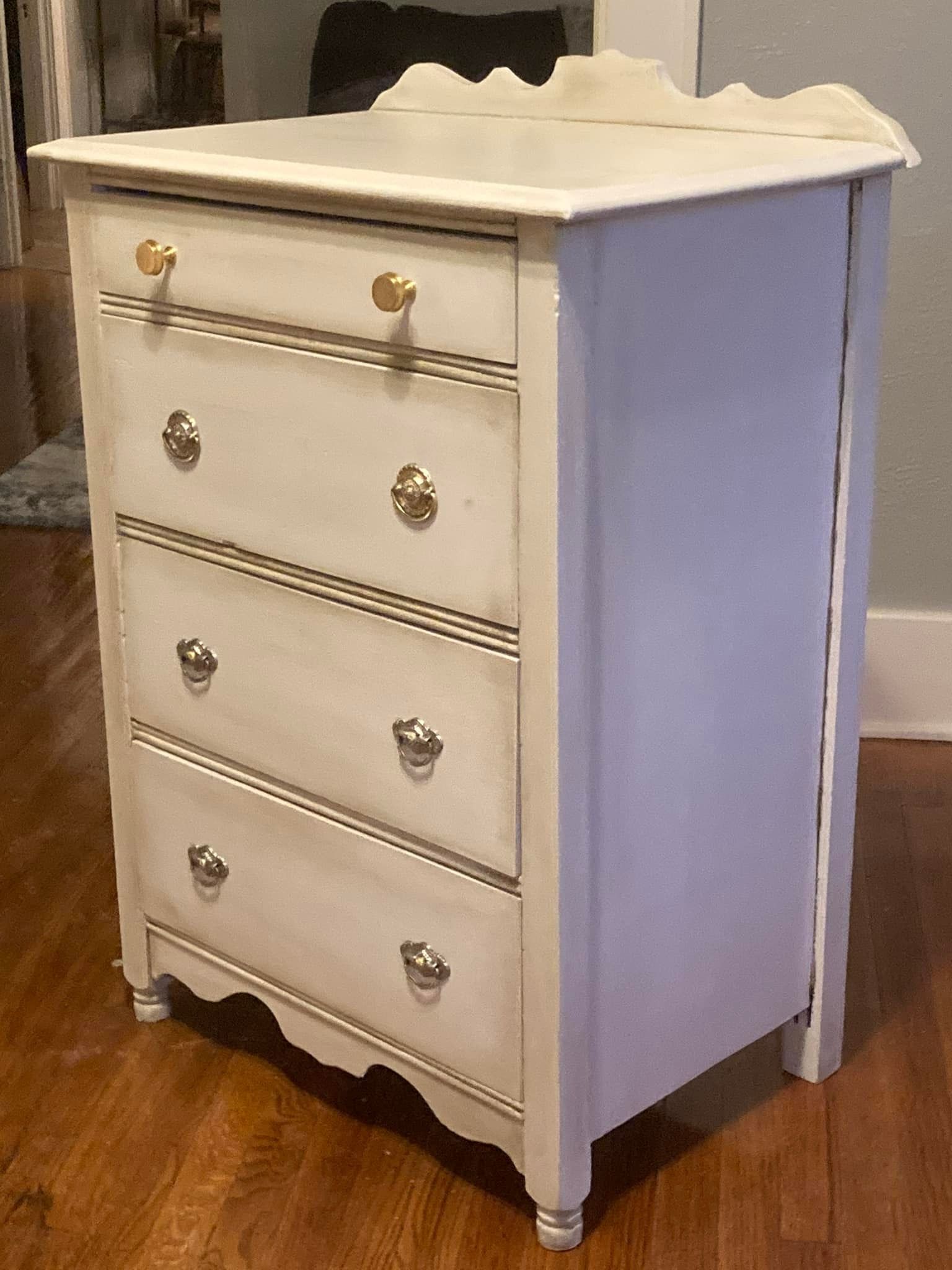 Painted white, antique chest of drawers with decorative hardware.