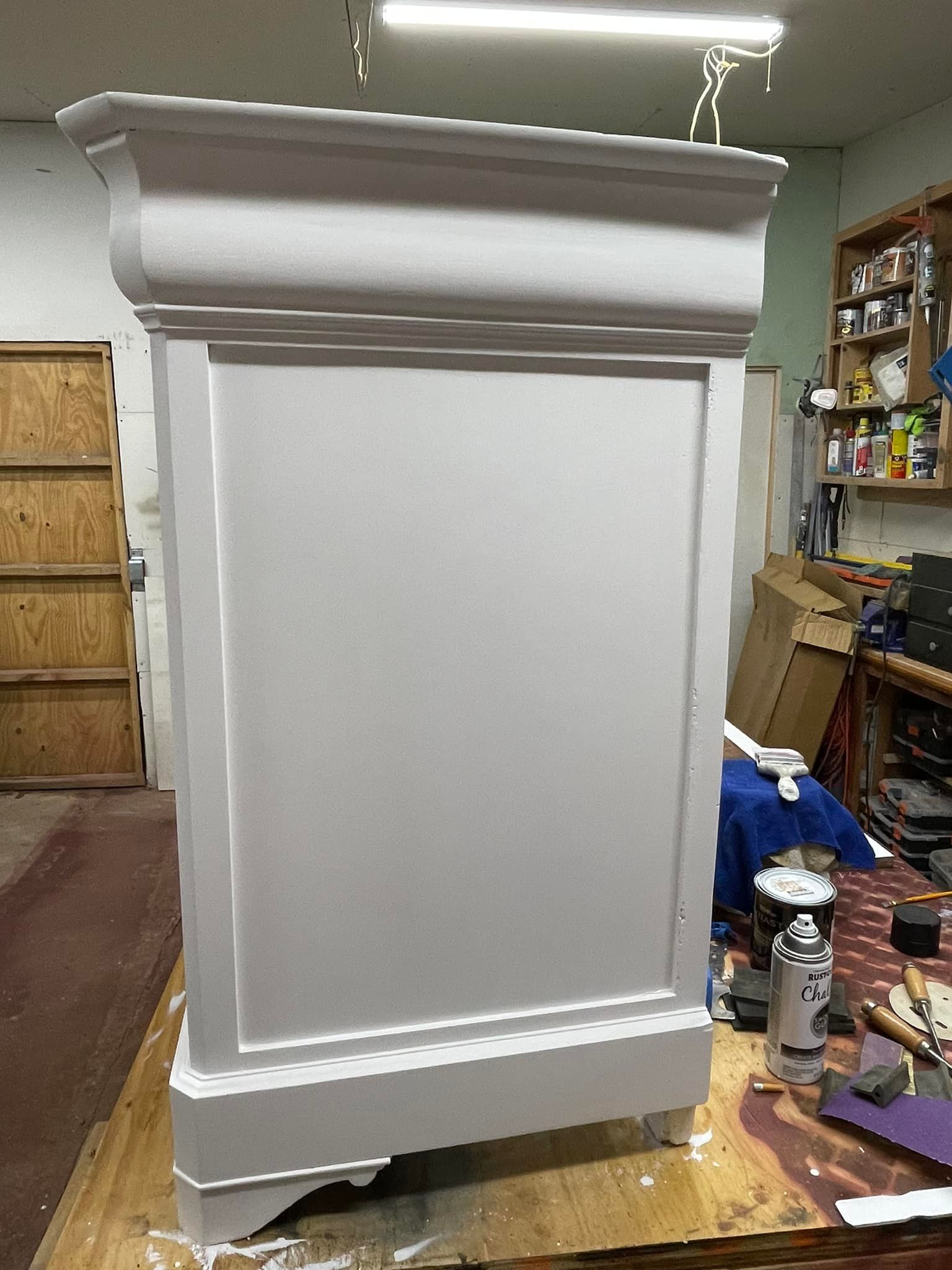 Gray painted cabinet, possibly an old fireplace mantel, in a workshop setting.