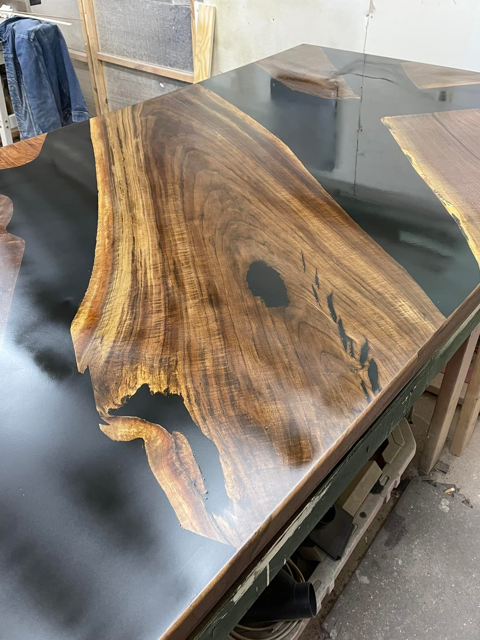 Wooden table with dark epoxy resin and a large, intricately patterned wood section.