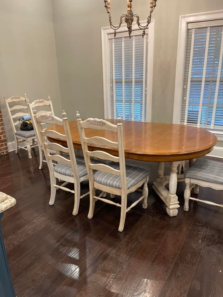 Dining table with six chairs in a room with windows and wood flooring.