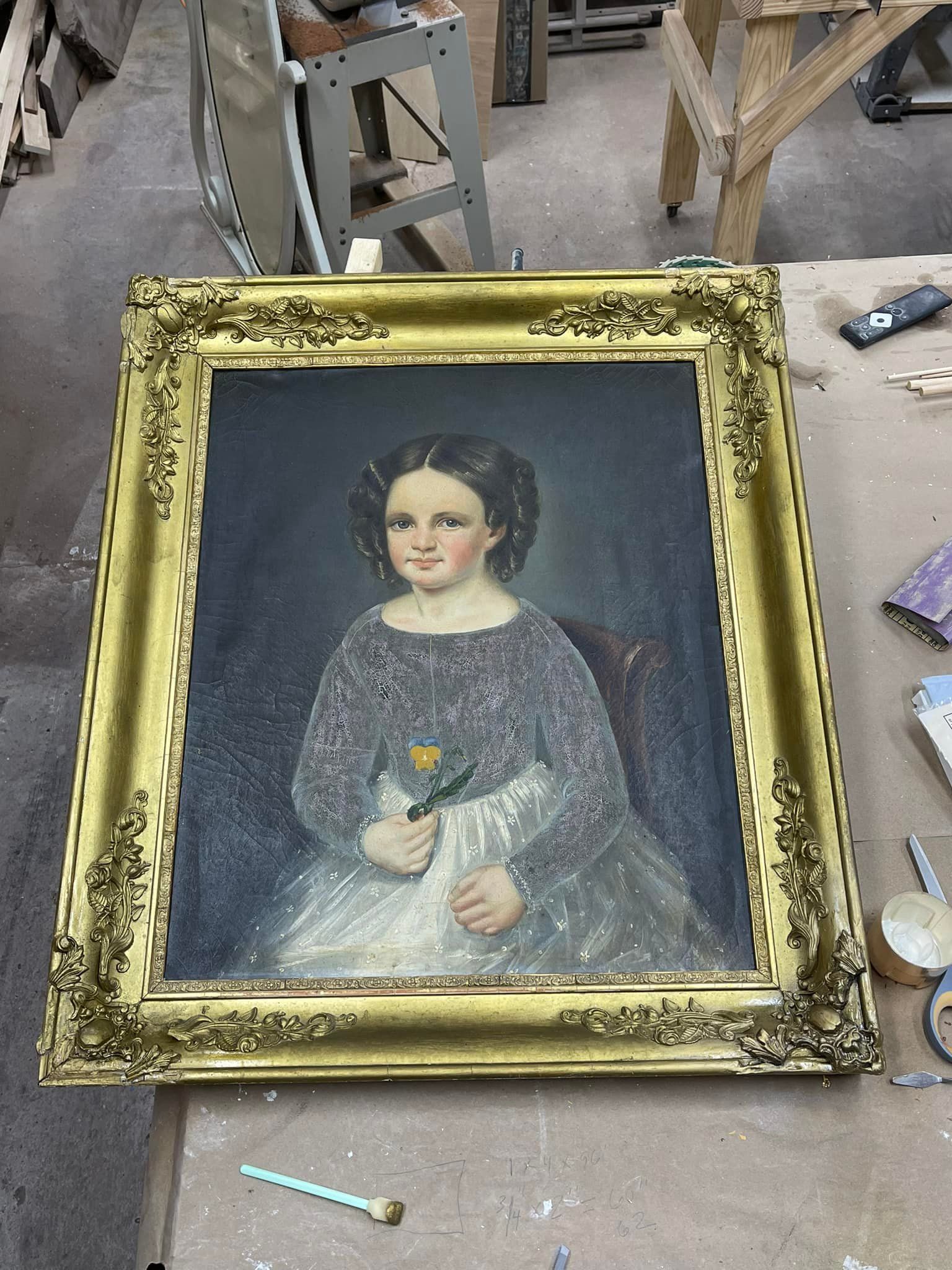 Oil portrait of a young girl holding a flower, ornate gold frame.