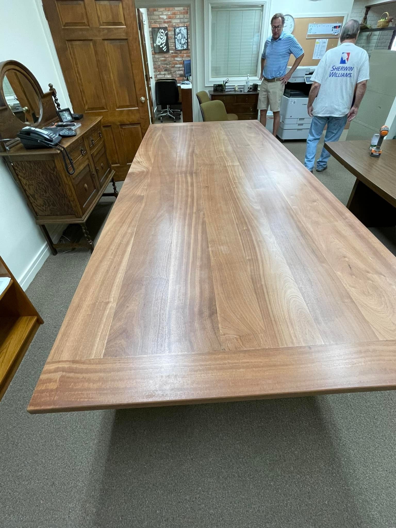Large wooden table in a room with two men standing nearby.
