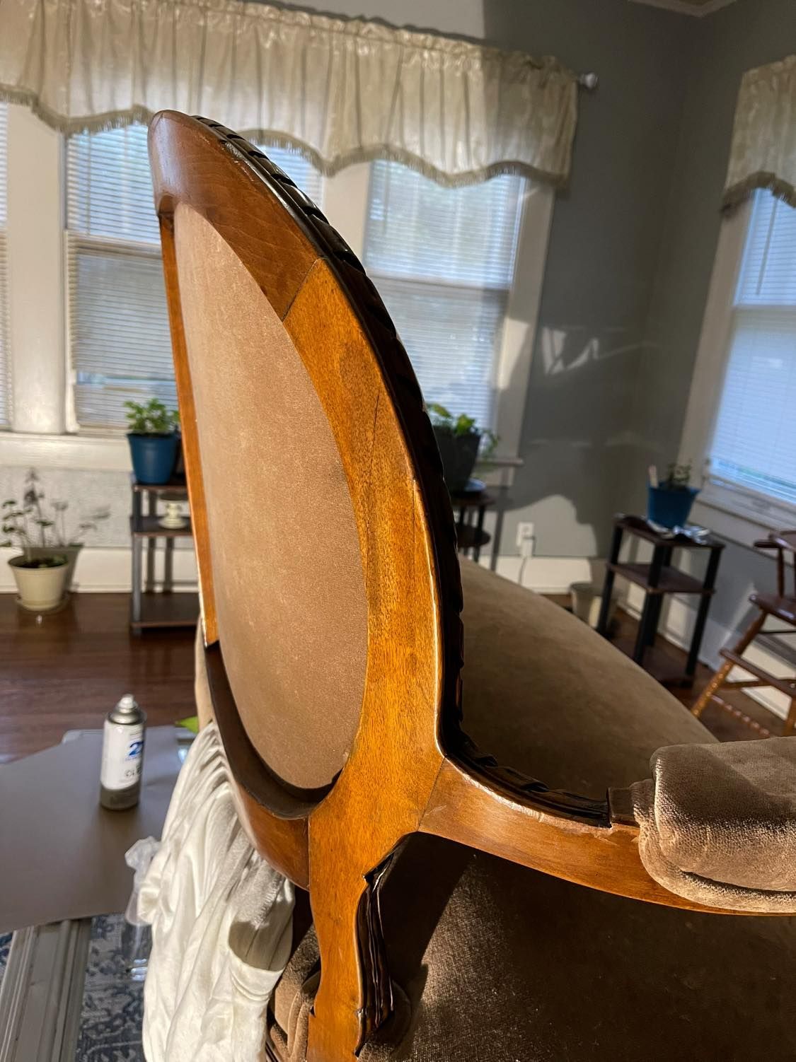 Wooden-framed armchair with brown velvet upholstery, viewed from the side, indoors near a window.