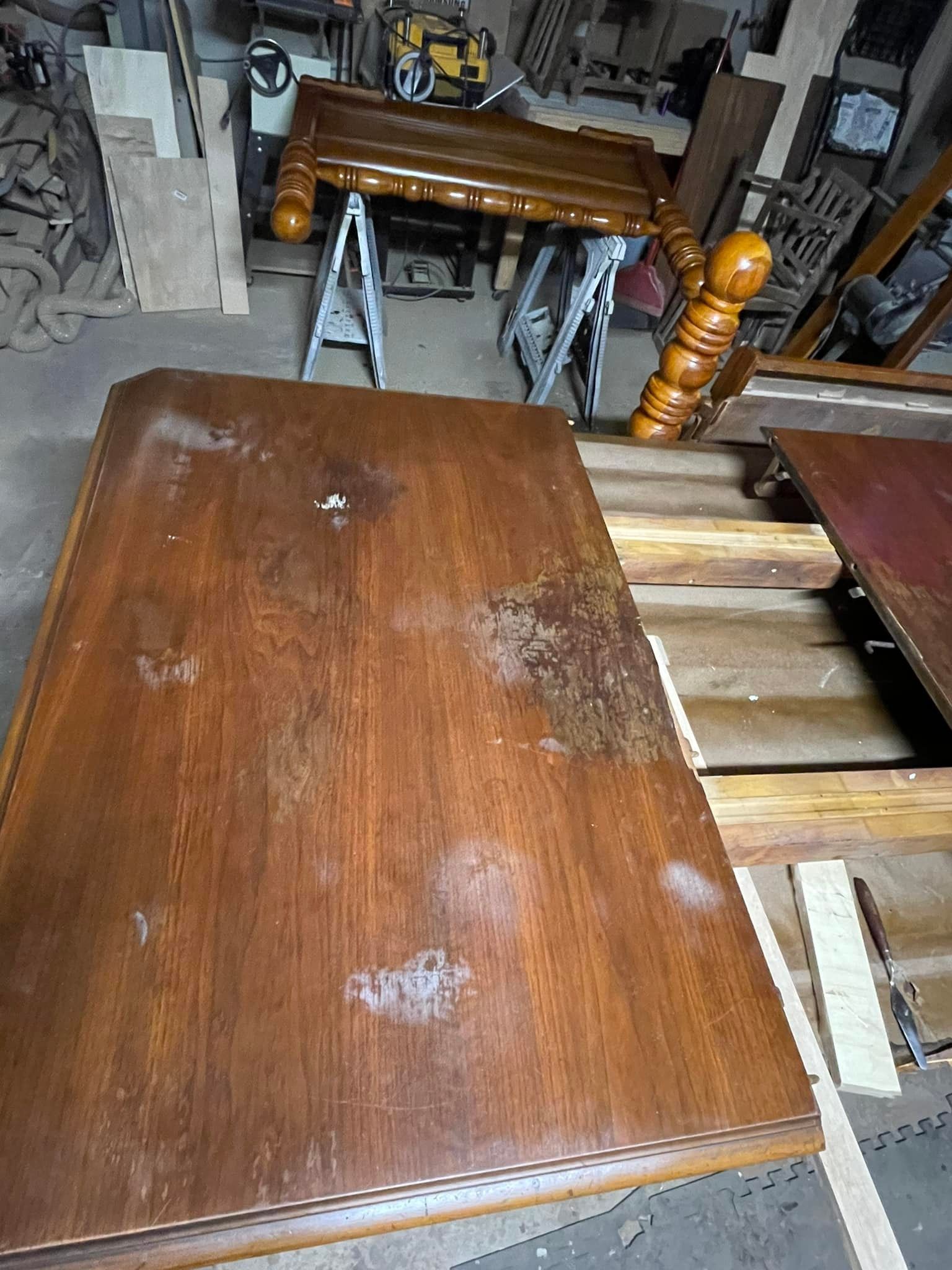 Wooden table with distressed surface; furniture parts and workshop setting.