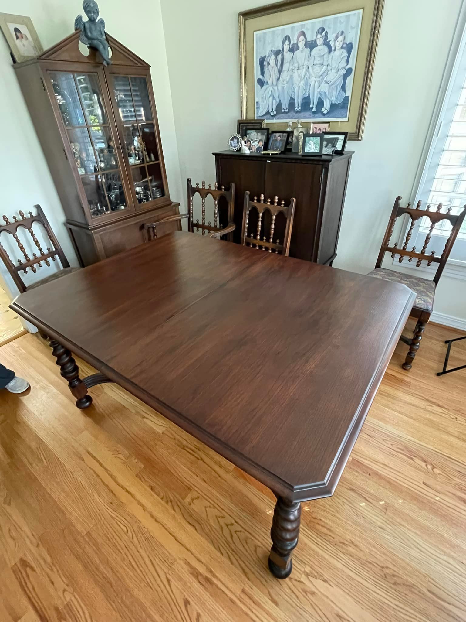 Dining room with dark wood table, chairs, and display cabinet on a hardwood floor.