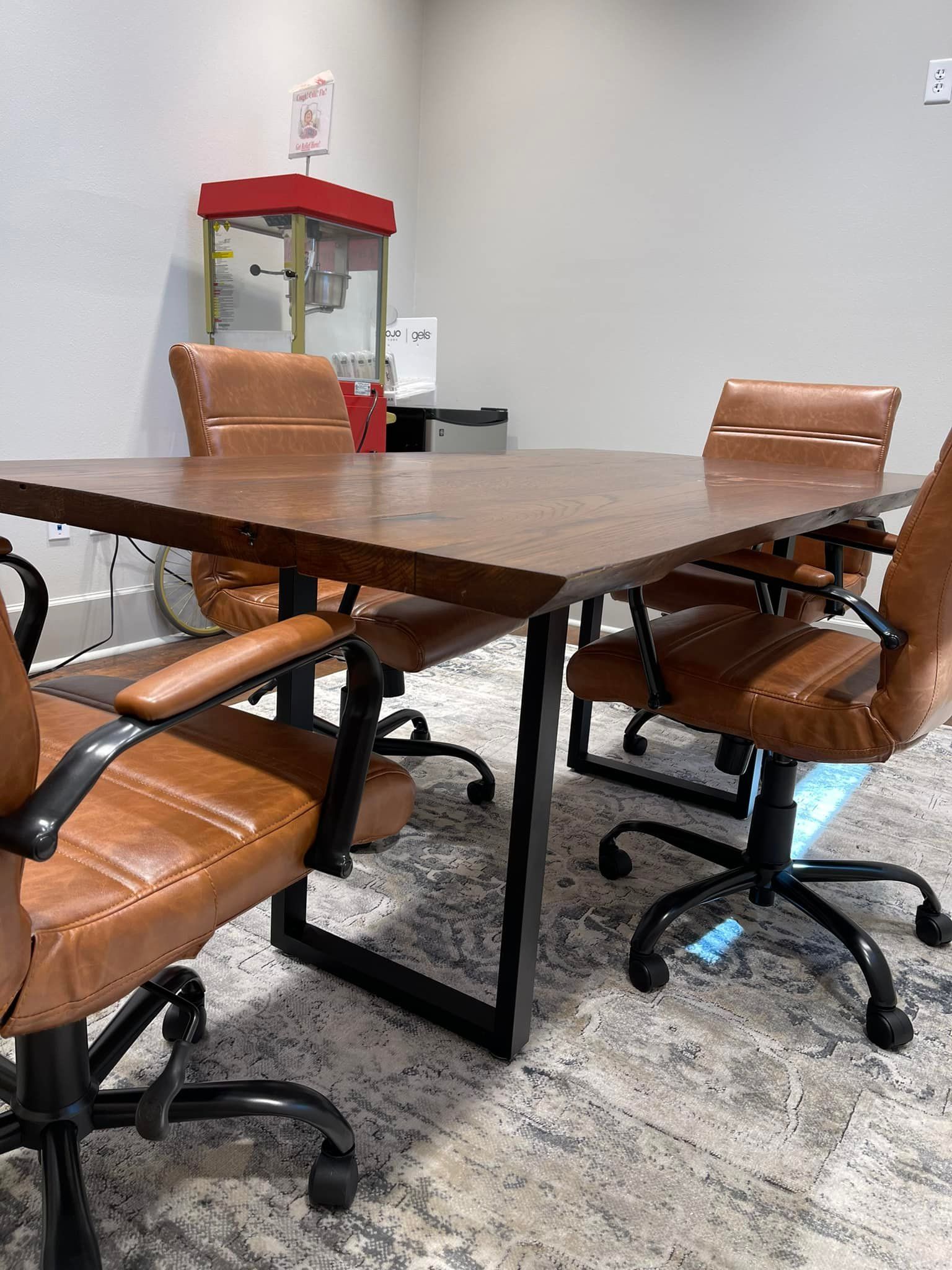 A conference room with a wooden table, leather chairs, and a popcorn machine.