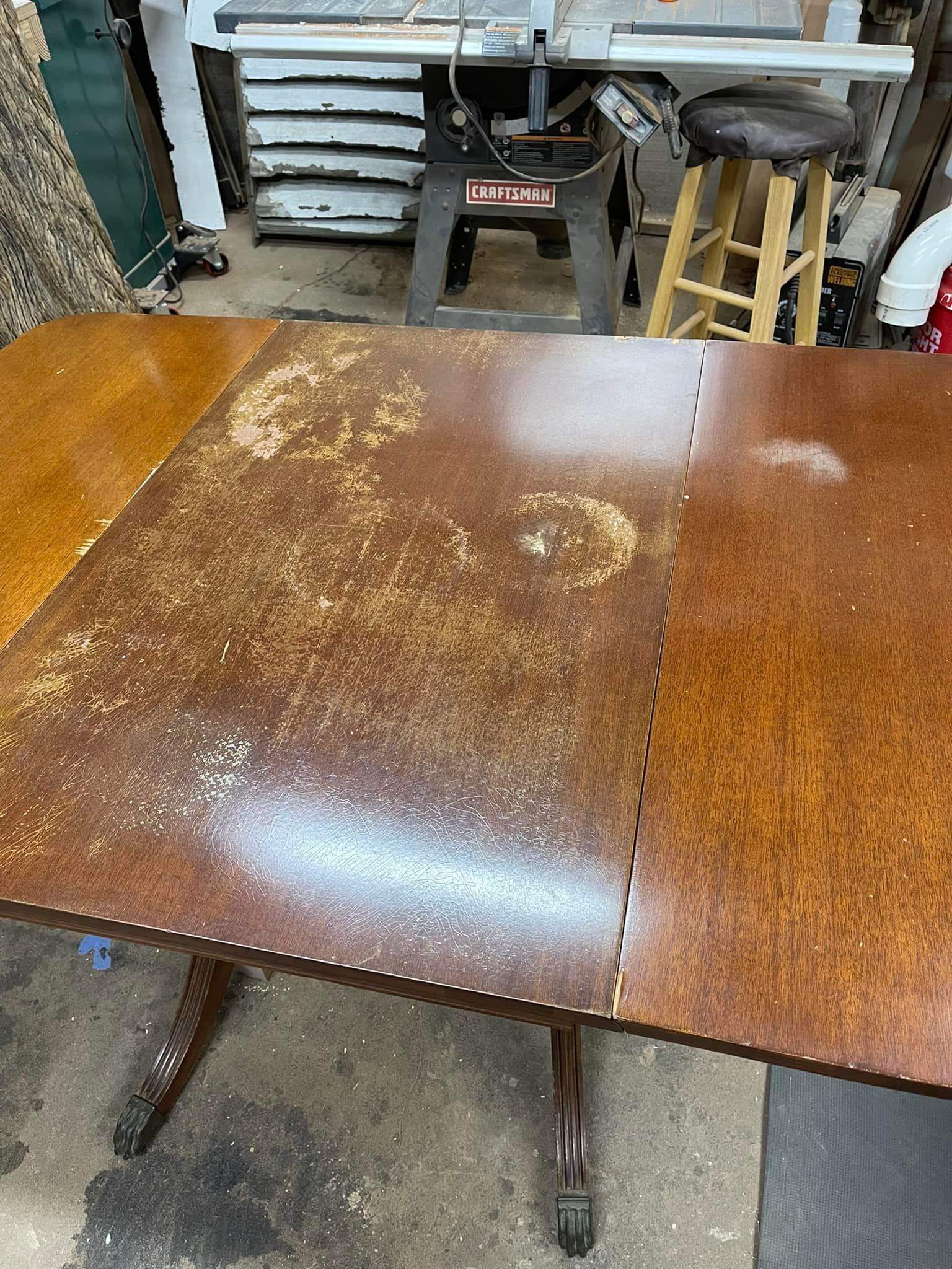 Brown wooden table with damaged surface in a workshop setting.