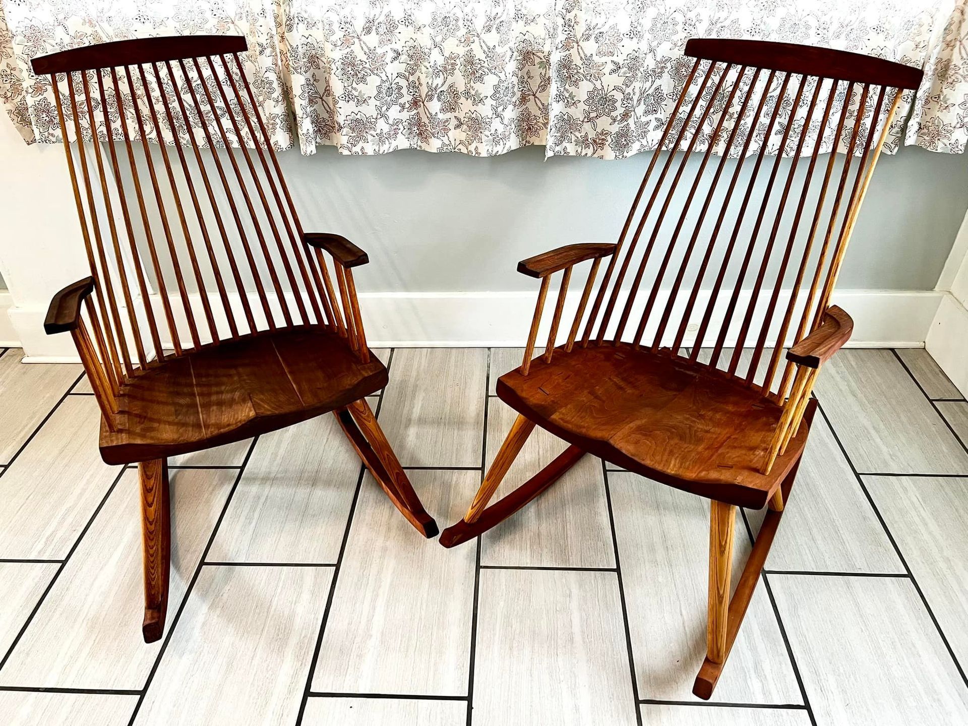 Two wooden spindle-back chairs with dark wooden seats and light legs on a tiled floor.
