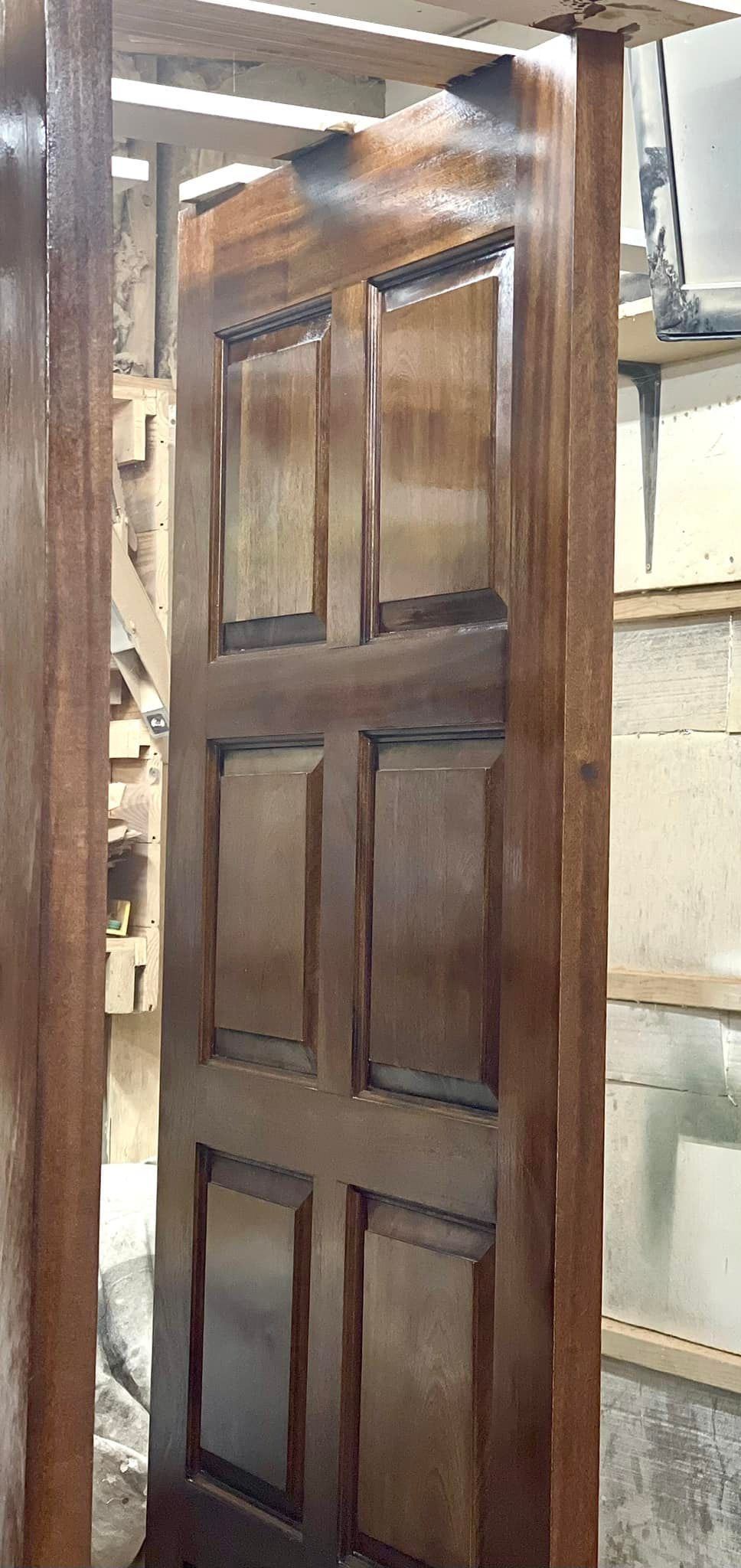 A dark brown wooden door, in a wooden frame.