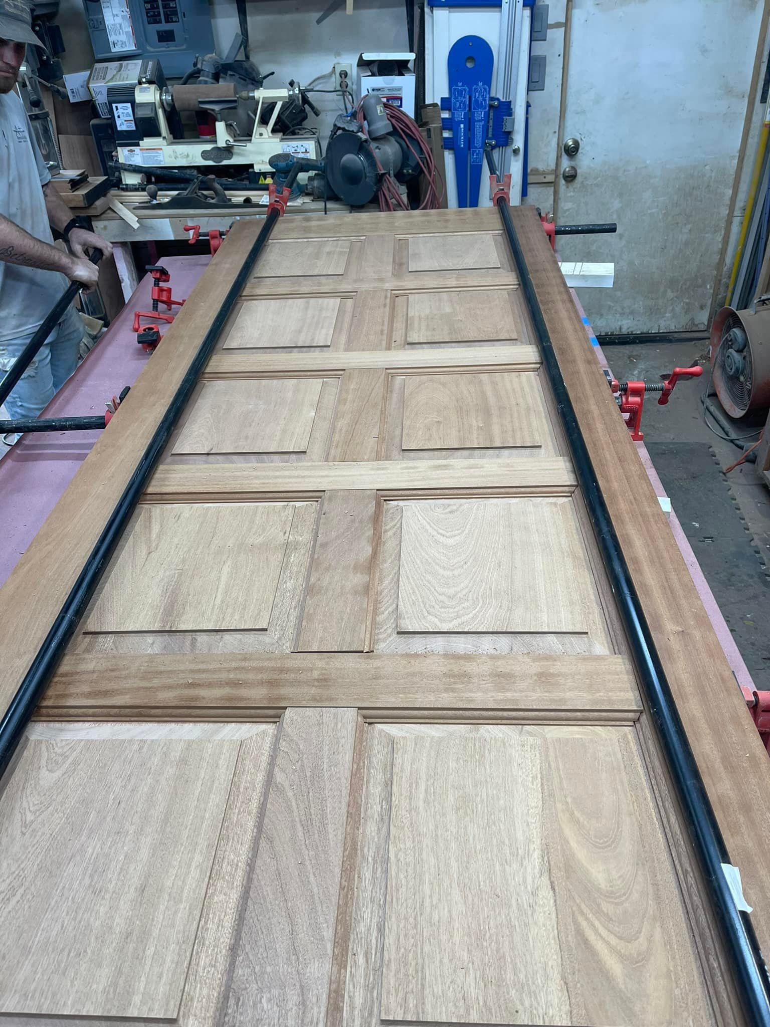 Wooden door being worked on with clamps in a workshop.