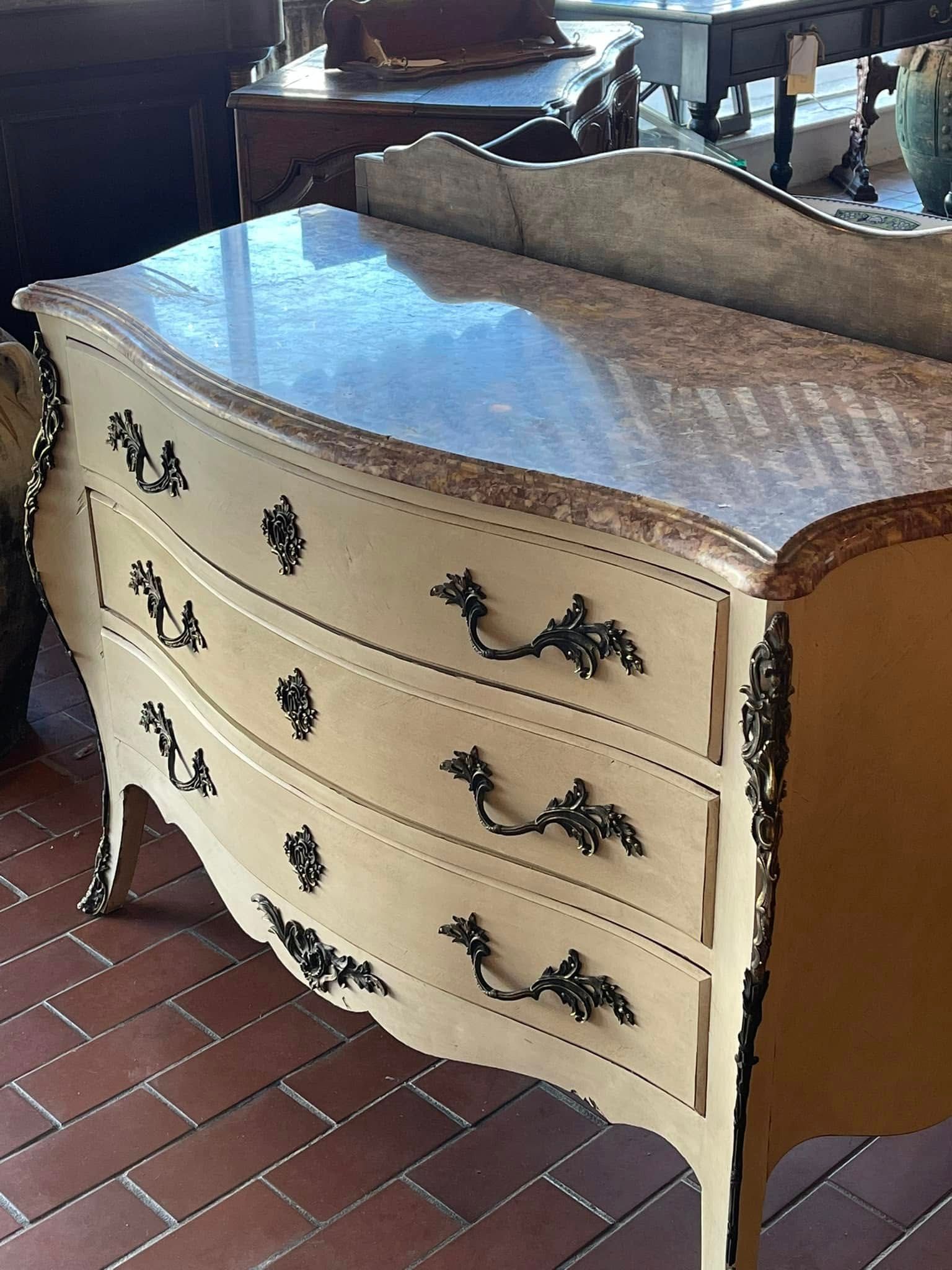 Cream-colored antique dresser with three curved drawers, black handles, and marble top.