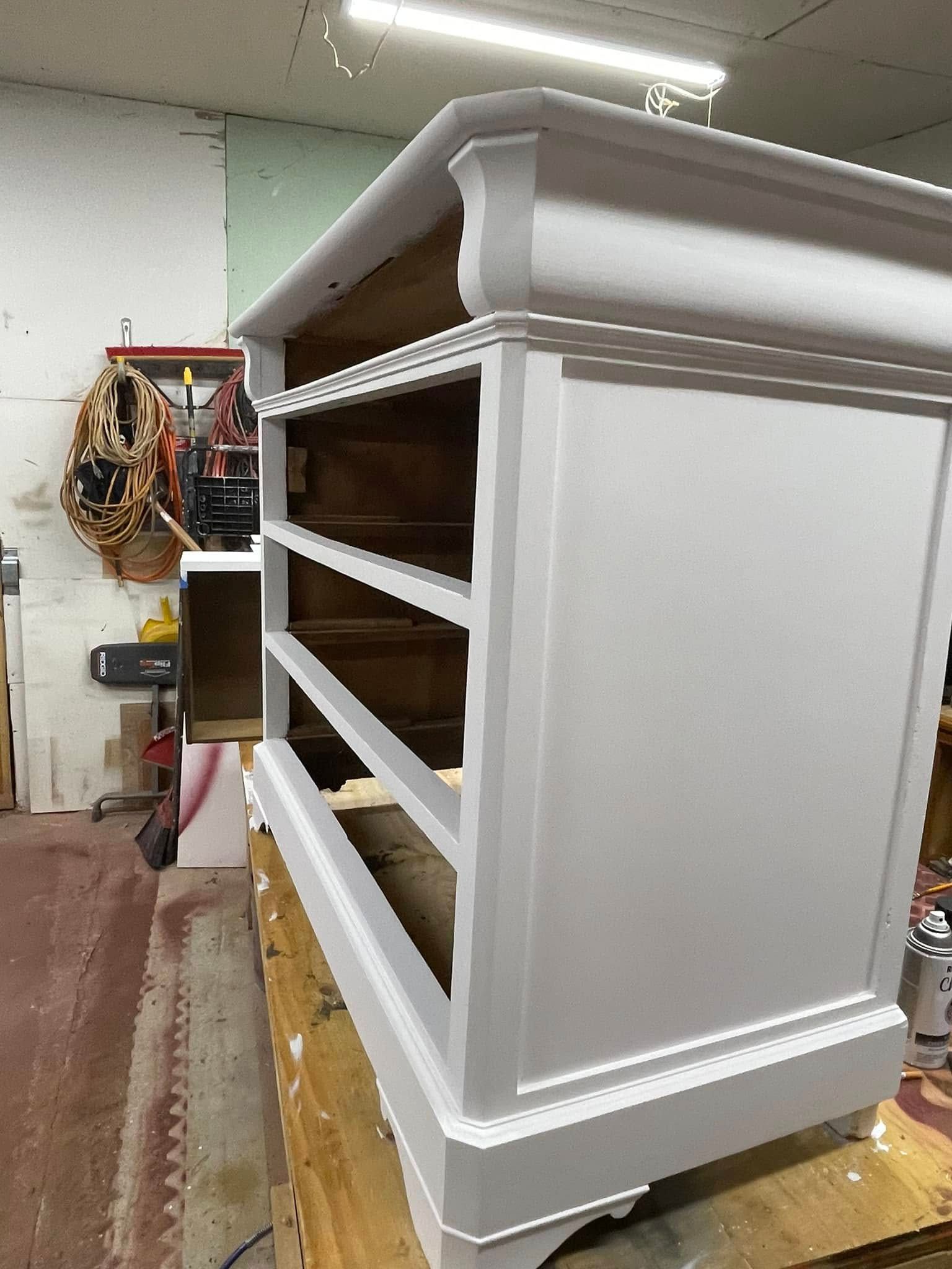 White painted dresser with open drawers in a workshop.