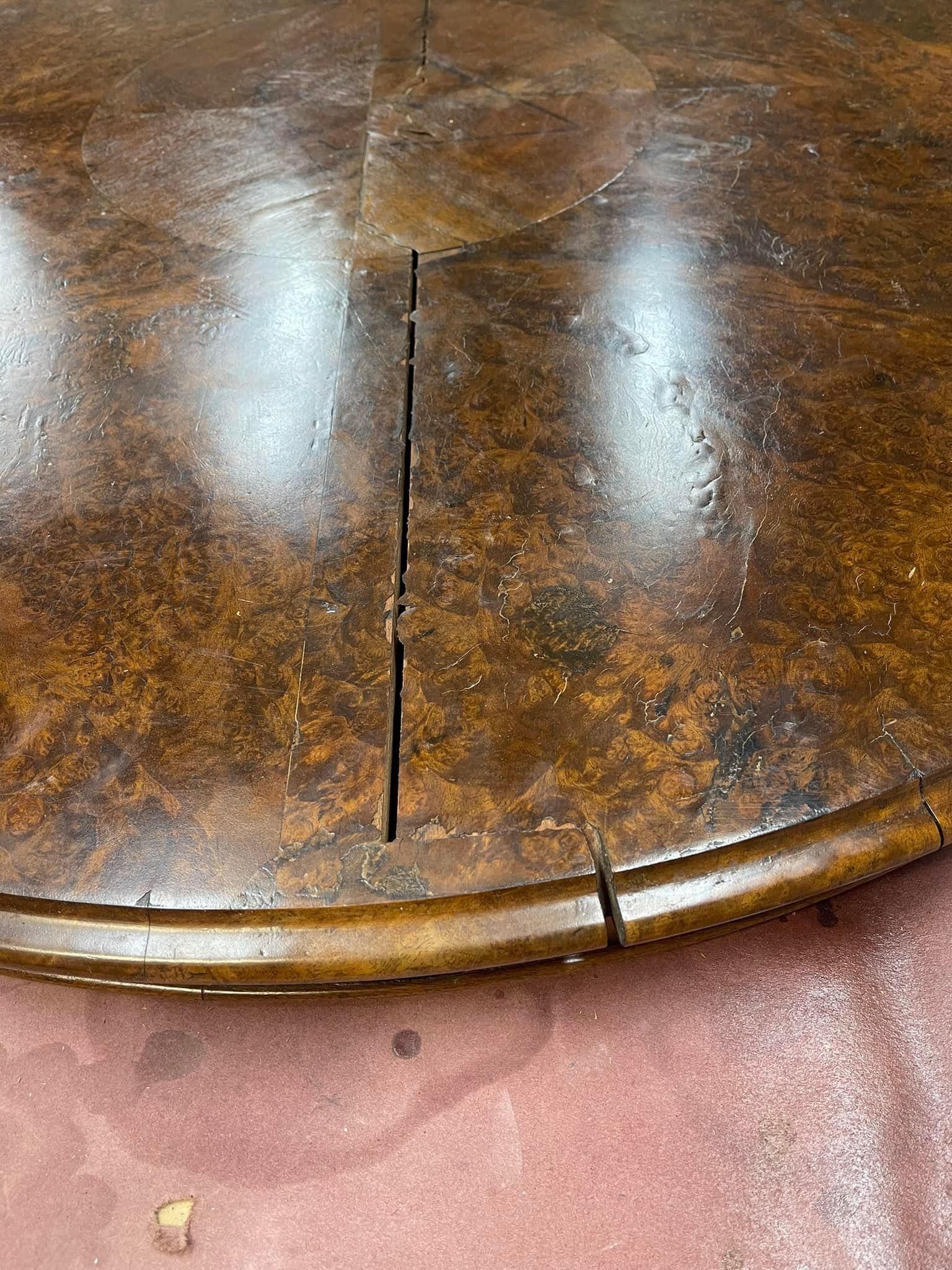 Close-up of a round, dark brown wooden table with cracks. Shiny surface reflecting light.