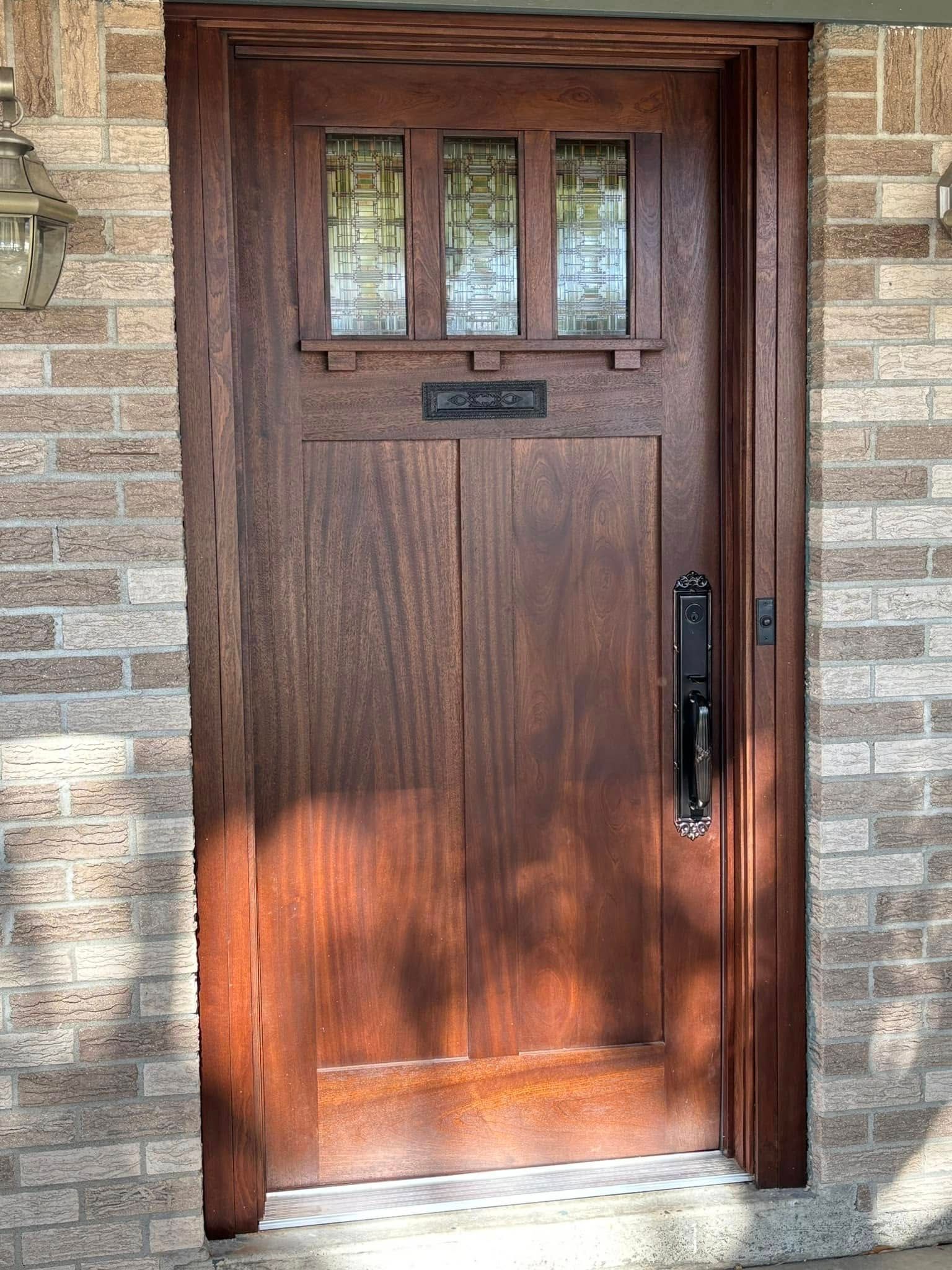 Wooden Craftsman-style door with small glass window panes. Brick exterior.