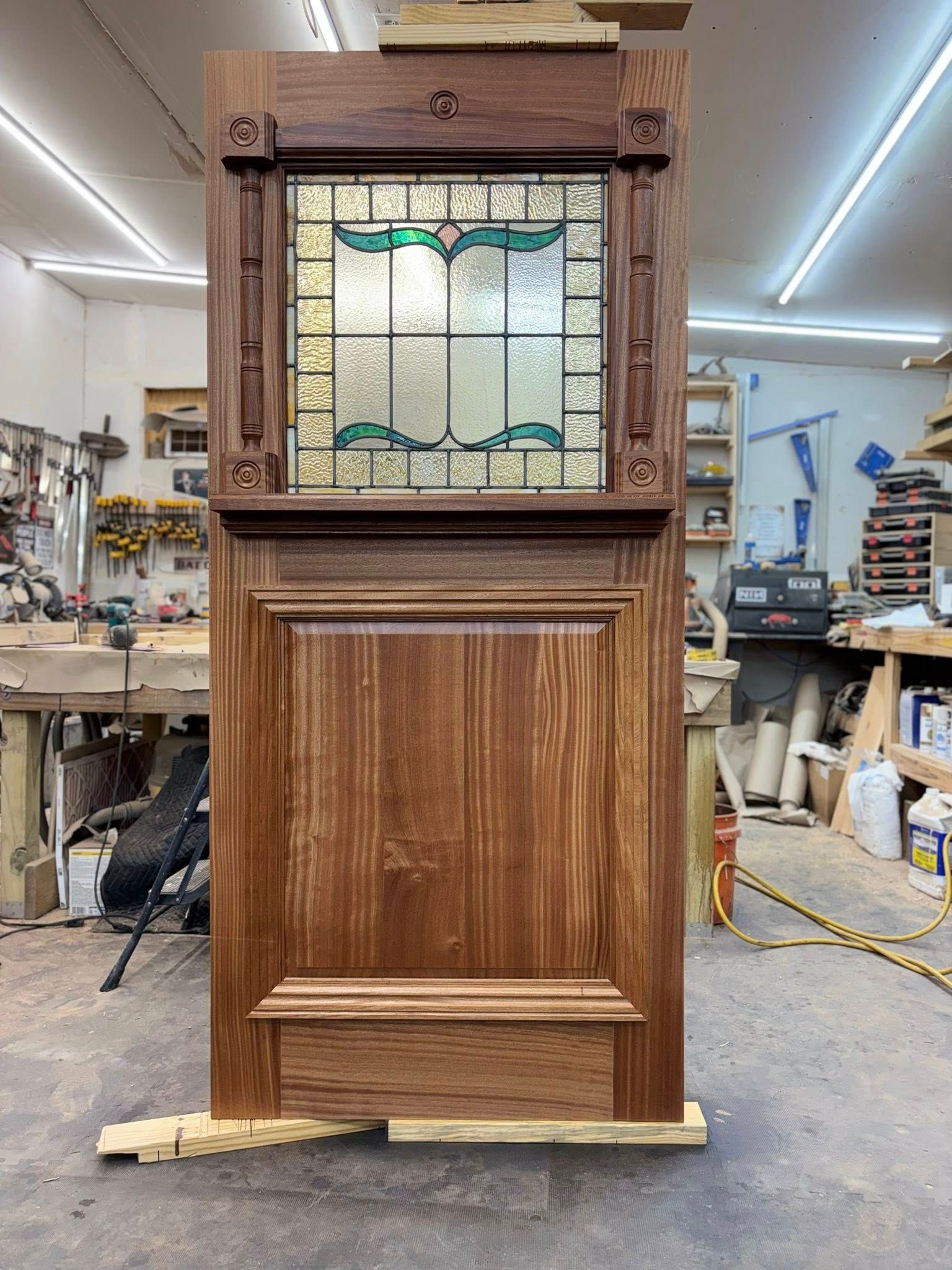 Wooden door with stained glass window, set in a wood workshop.
