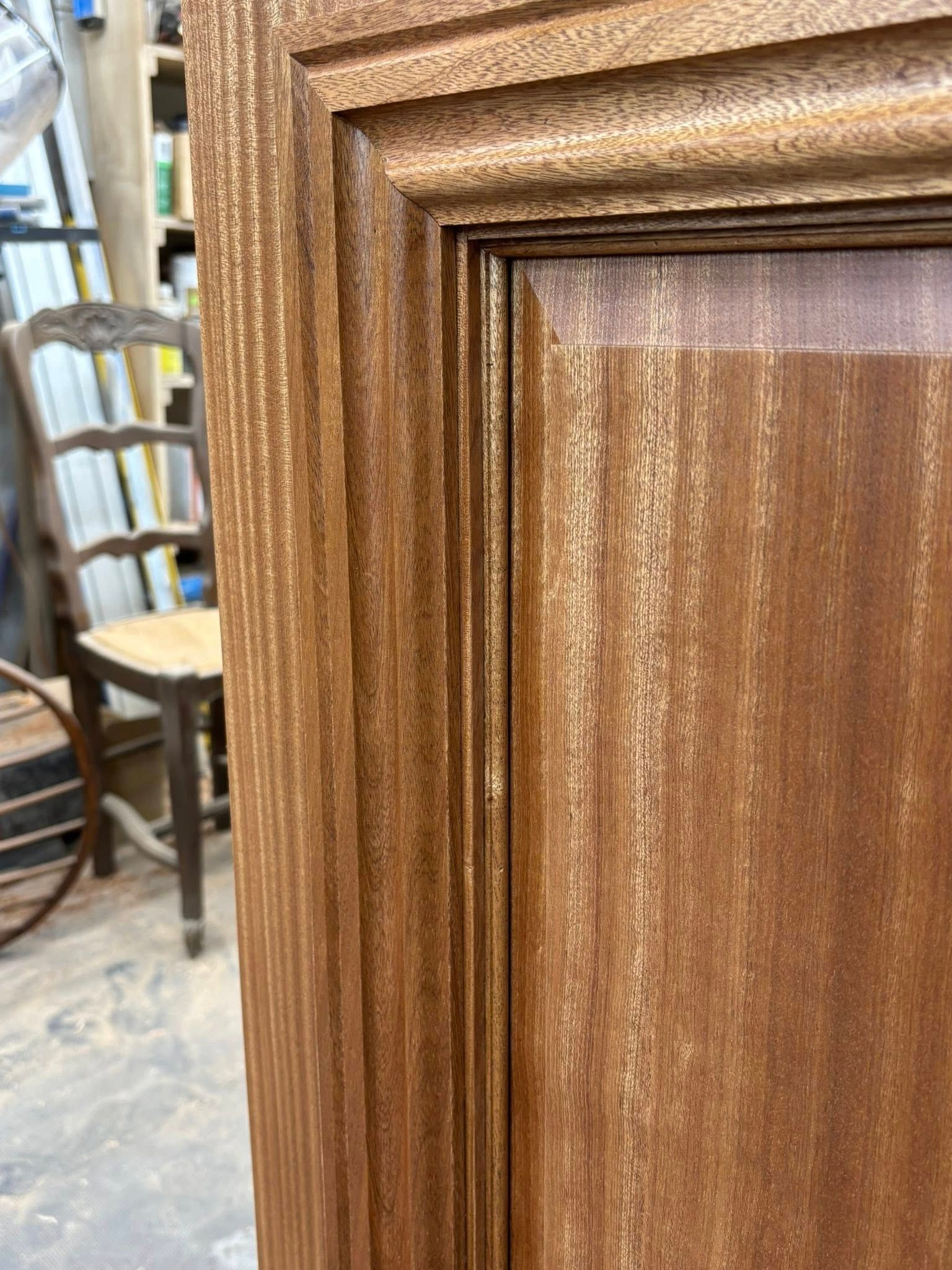 Close-up of a wooden cabinet door with detailed carved paneling. Brown wood grain.