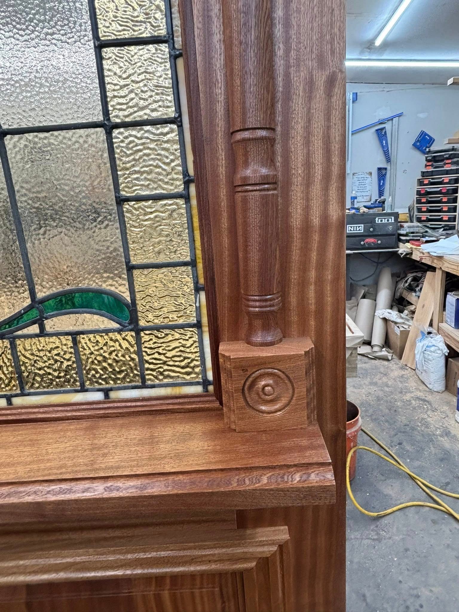 Close-up of a stained wood trim with a decorative accent and a stained glass window.