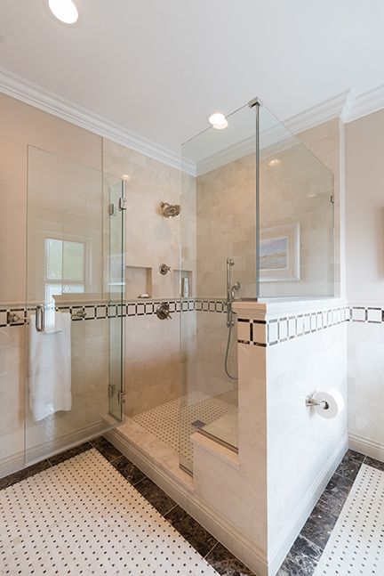 Glass shower enclosure with white tile and a step-up entrance.