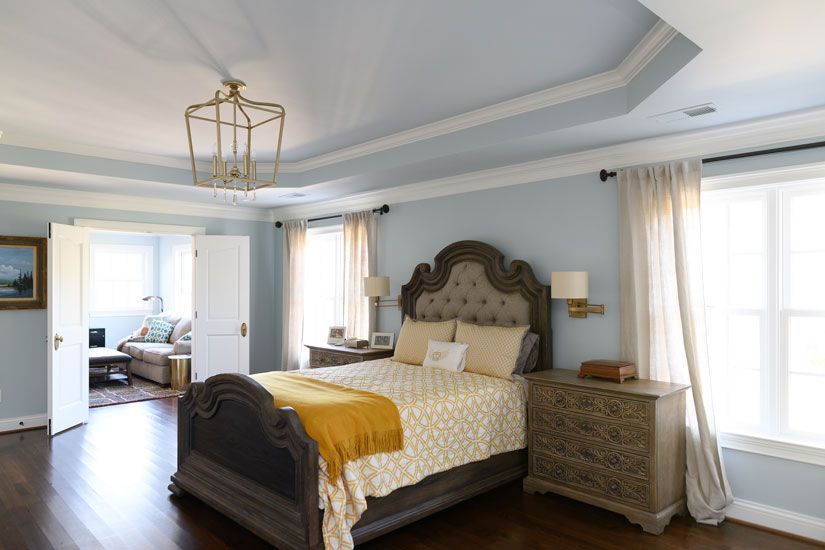 Bedroom with a tufted headboard bed, light blue walls, and a gold chandelier.