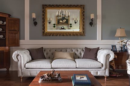 Living room with a tufted sofa, framed mirror, and wooden furniture.