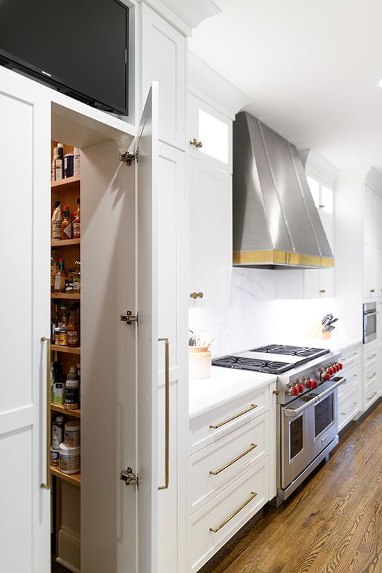 White kitchen with a pull-out pantry and stainless steel range hood.