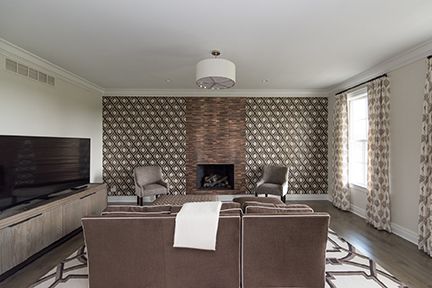 Modern living room with fireplace, patterned accent wall, sofa, chairs, and TV.