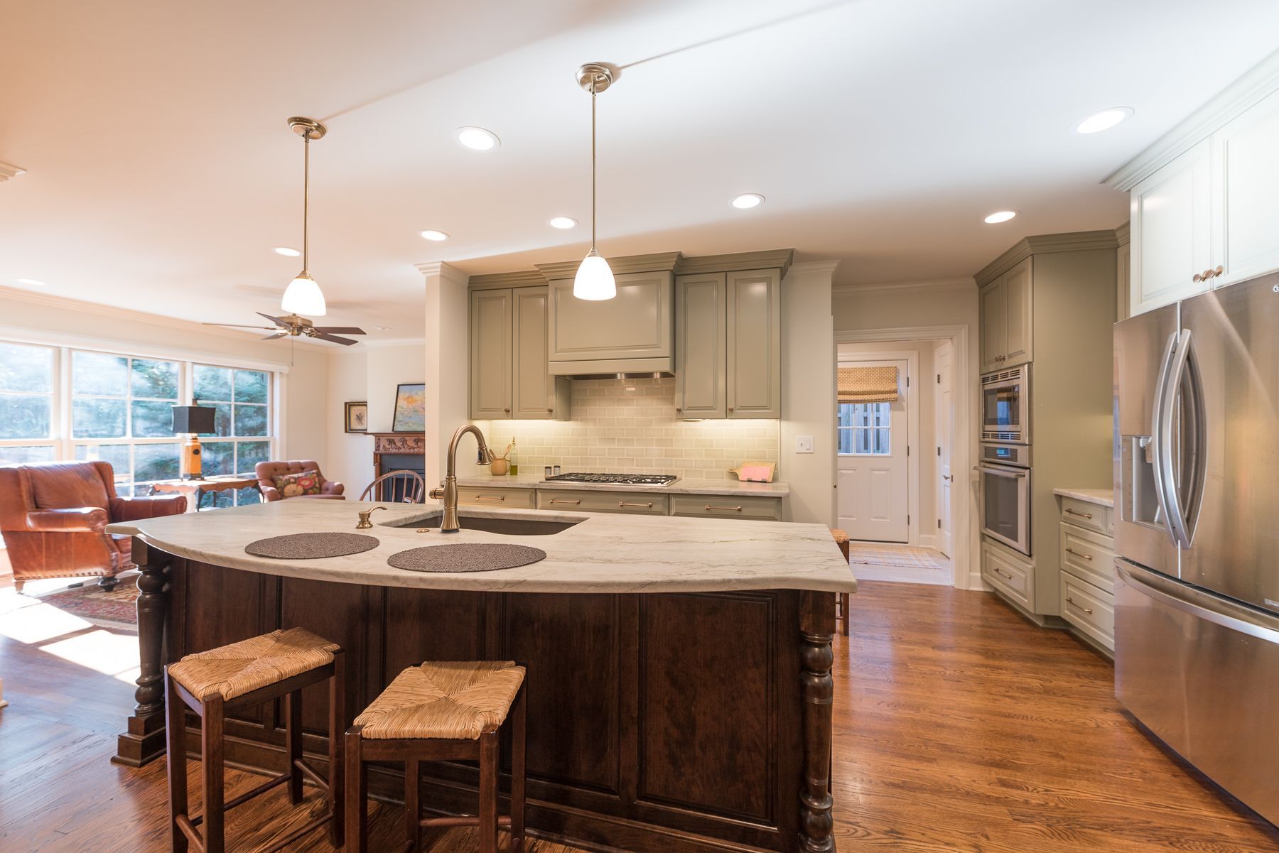 Kitchen with island, cabinets, and stainless steel appliances; light green cabinets, hardwood floors.