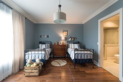 Bedroom with two twin beds, blue walls, wood floors, and a baseball rug.