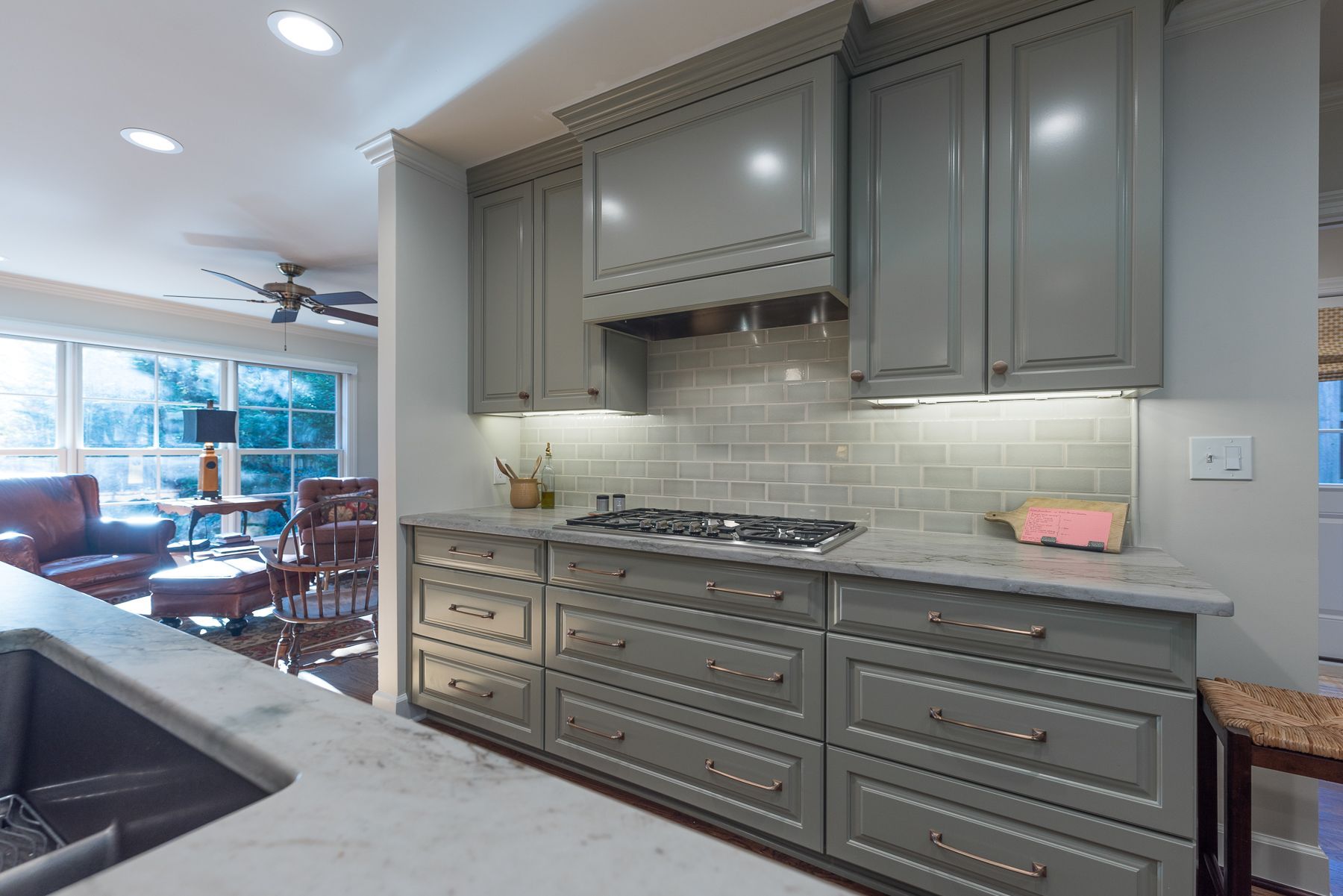Gray kitchen with cabinets, marble countertops, and a view to a living room.