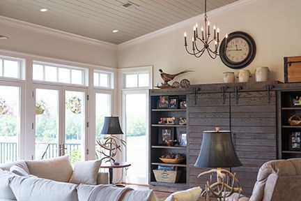 Living room with large windows, gray sliding barn door, chandelier, and neutral color scheme.