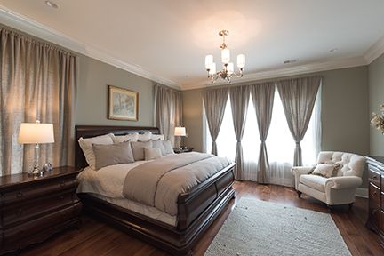Elegant bedroom with a dark wood bed, gray walls and curtains, and a white armchair.