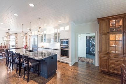 Spacious kitchen with island, white cabinets, hardwood floors, and built-in appliances; a laundry room is visible.