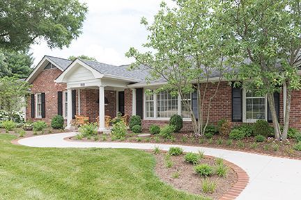 Brick house with a curved walkway, porch with columns, and landscaping.