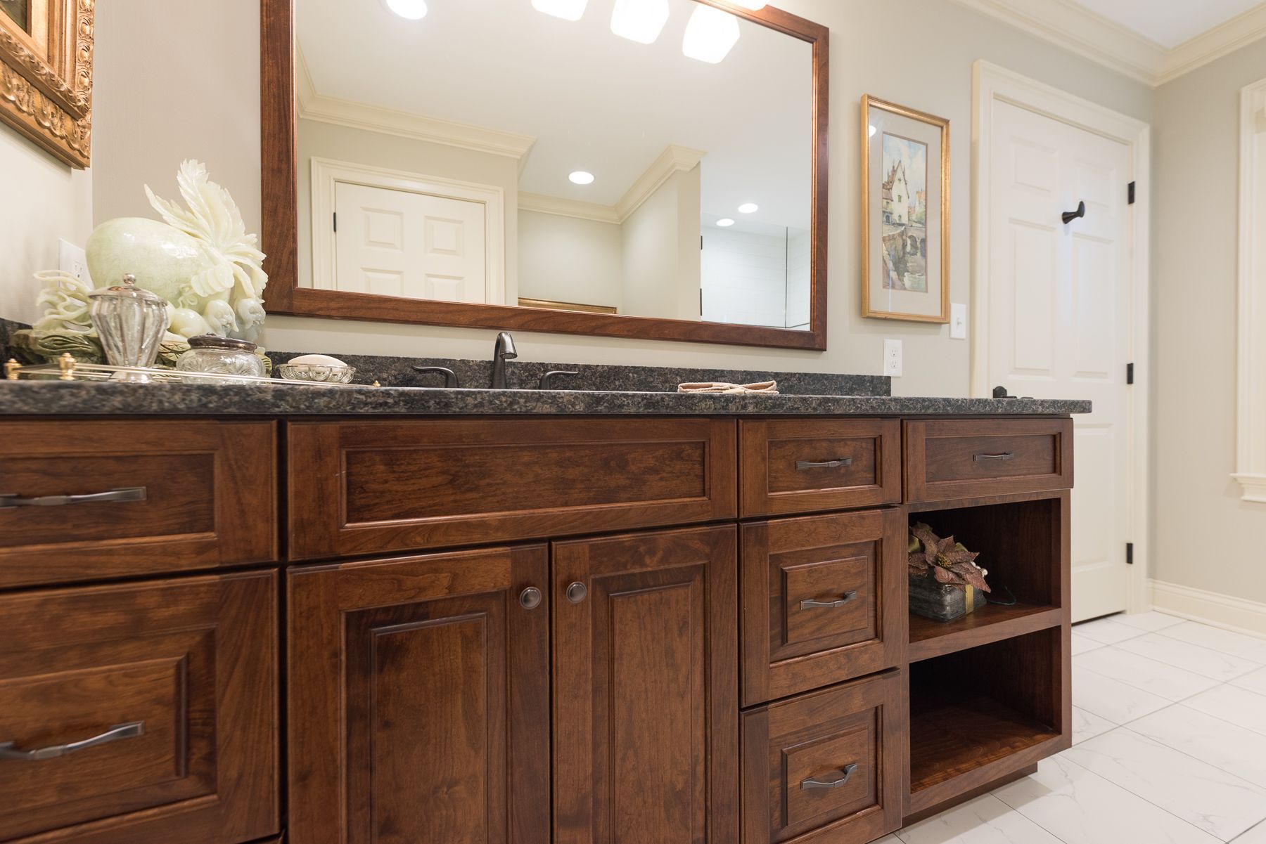 Bathroom vanity with dark wood cabinets, black countertop, and large mirror.