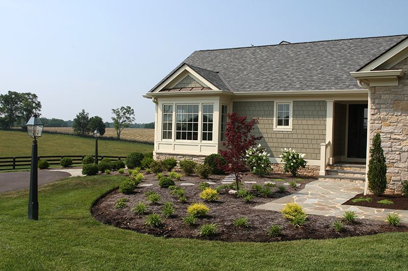House exterior with landscaping, featuring a stone facade, bay window, and flower beds.